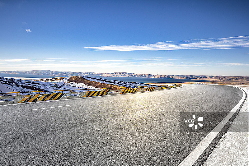 一条柏油公路从高原雪山脚下穿行而过图片素材