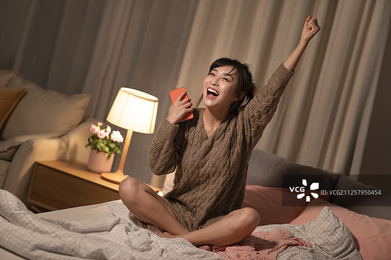 年轻女士在家玩手机游戏图片素材