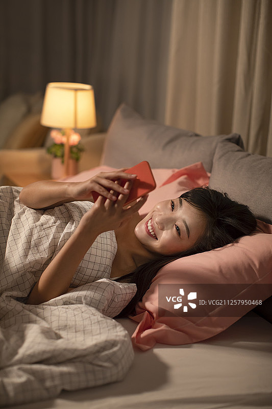 年轻女士睡前玩手机图片素材