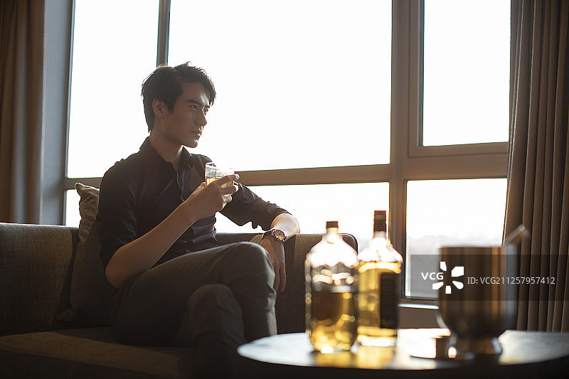 年轻商务男士在房间喝酒图片素材