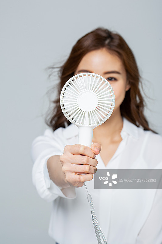白色背景下的夏季女人与便携式风扇。图片素材