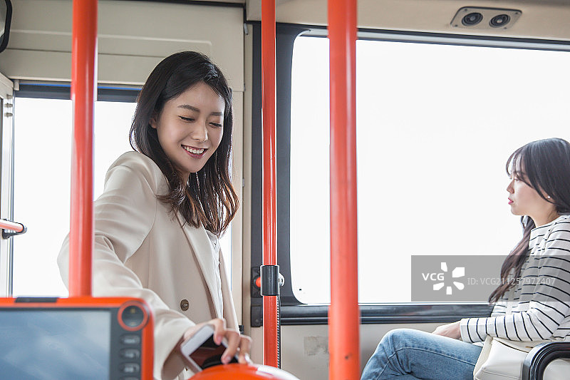 乘坐公共交通工具的微笑女人正在使用智能手机图片素材