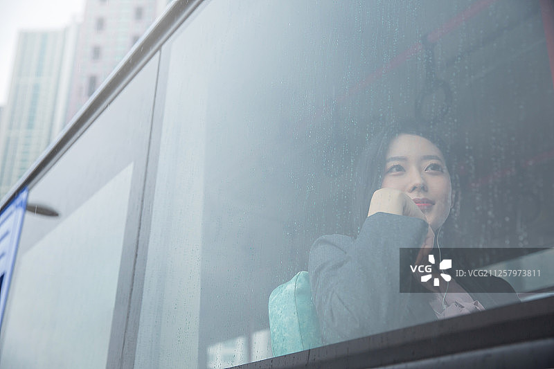 车内，女人坐在巴士上靠窗听音乐图片素材