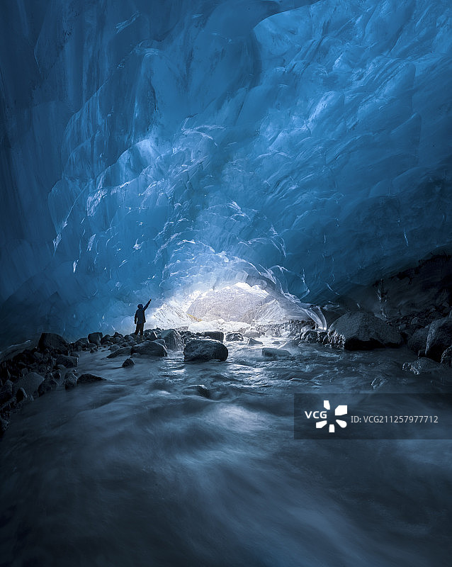 阿拉斯冰川天蓝冰洞中站立的一个人图片素材