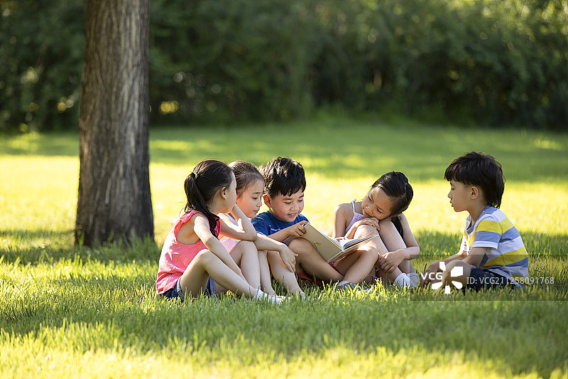 快乐的儿童在草地上读书图片素材