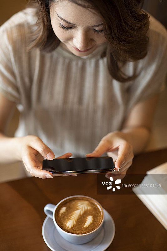 优雅女士在咖啡店使用手机拍照图片素材