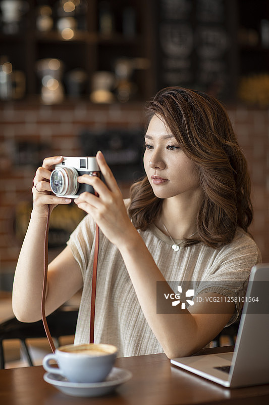 优雅女士在咖啡店使用相机图片素材