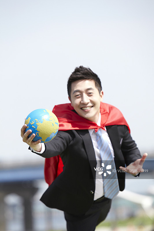 在汉江手持地球仪，披着超人斗篷的商人摄影图片素材