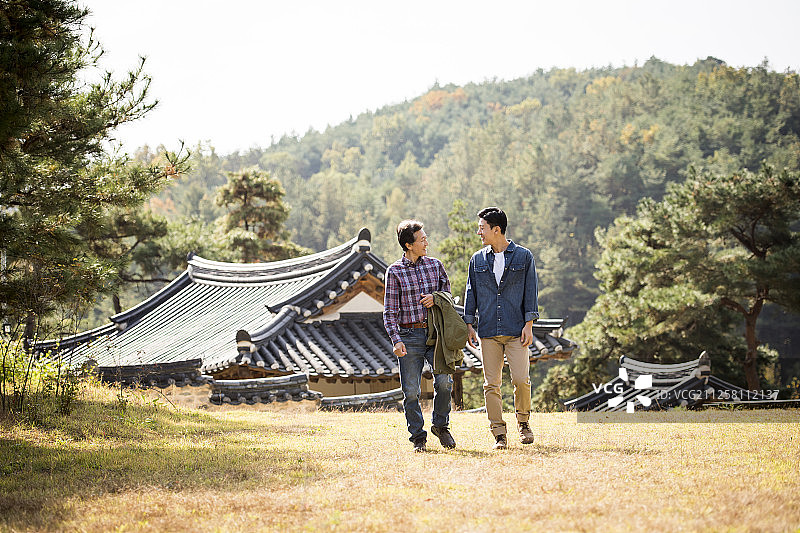 儿子和父亲在传统韩式房屋附近放松身心的户外摄影图片素材