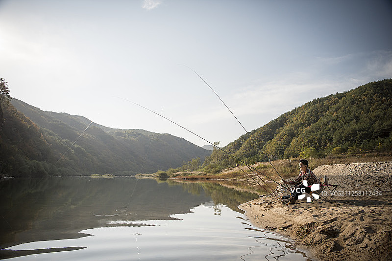 男子在河里钓鱼的照片图片素材