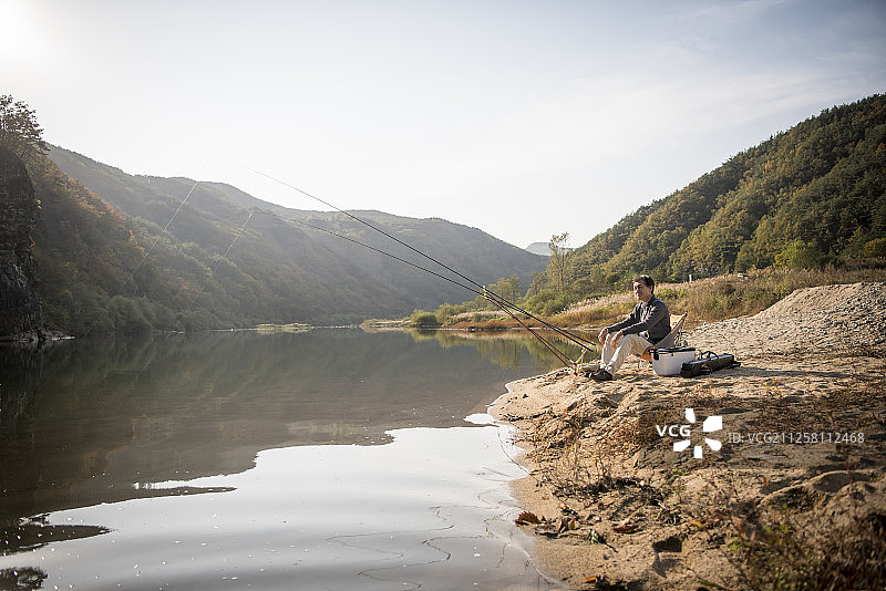男子在河里钓鱼的照片图片素材