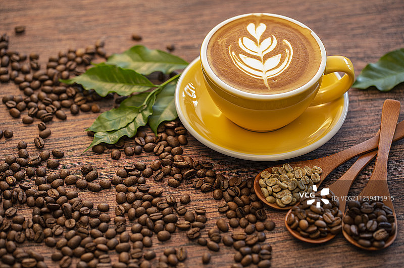 一杯含有漂亮拉花的拿铁咖啡和不同烘焙程度的咖啡豆图片素材