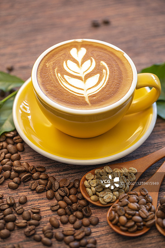 一杯含有漂亮拉花的拿铁咖啡和不同烘焙程度的咖啡豆图片素材
