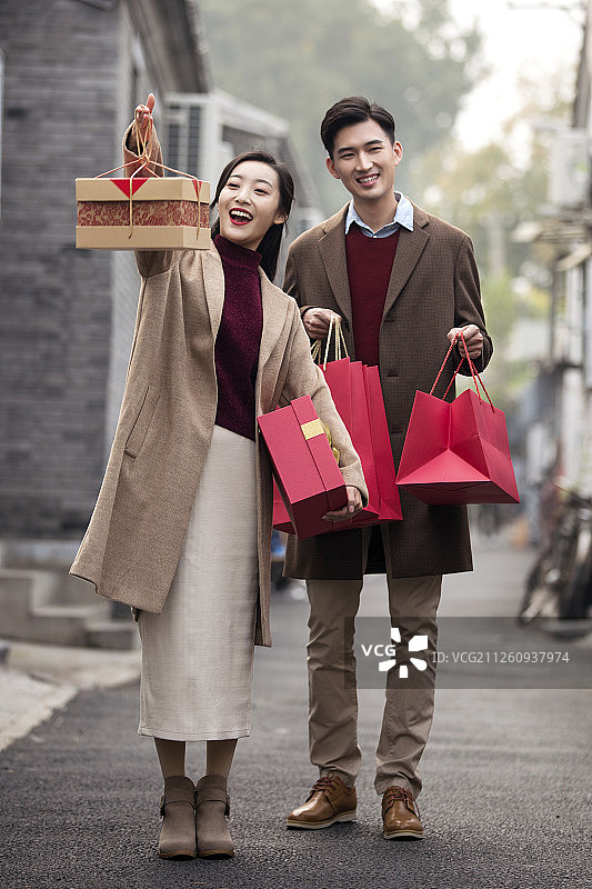 快乐的年轻情侣提着礼物图片素材