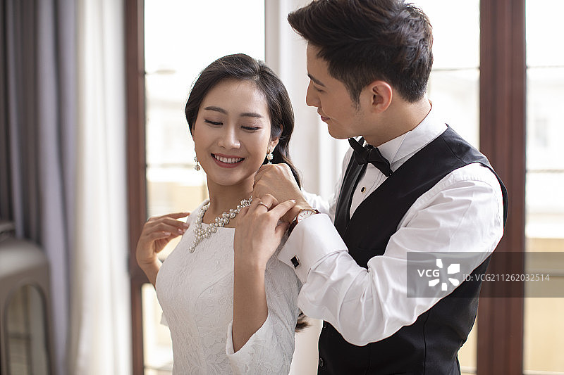 年轻男士帮妻子戴项链图片素材