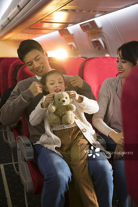一家三口在飞机上玩游戏嬉戏去度假旅行图片素材
