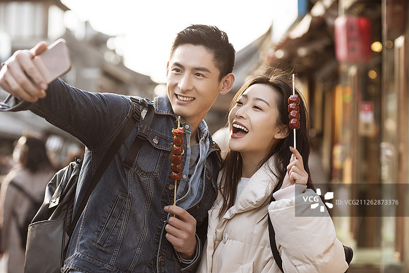 快乐的情侣在胡同用手机自拍图片素材