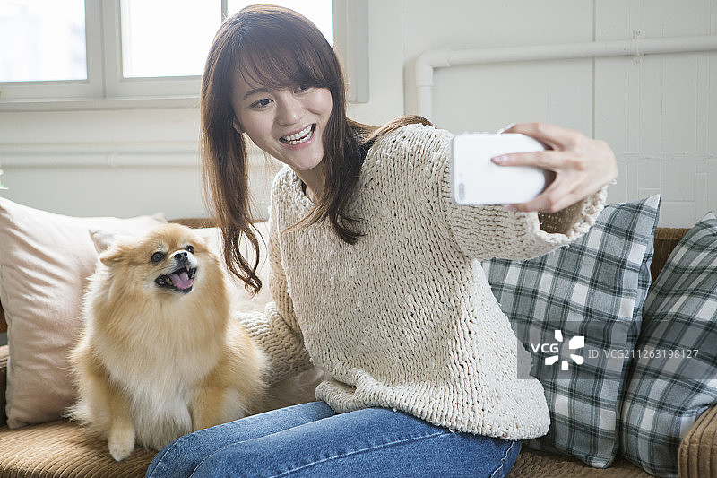 中年妇女在沙发上与狗自拍图片素材