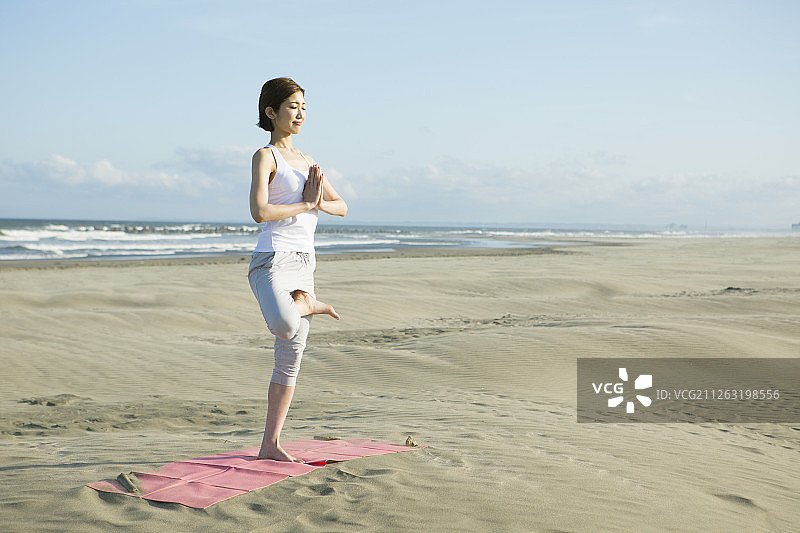 年轻女子在海滩上做瑜伽图片素材