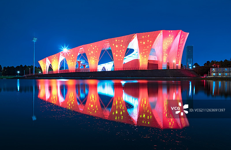 夜色下，东方体育中心跳水馆月亮湾的倒影和红底五角星夜景灯图片素材