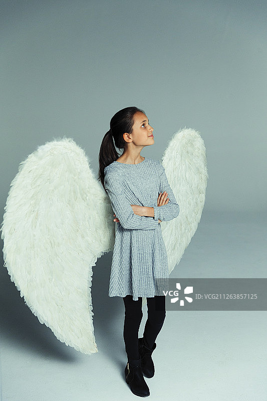 戴着天使翅膀，向上看的好奇自信女孩肖像图片素材