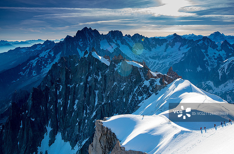 清晨阳光中，一队全副武装的登山队员行走在阿尔卑斯雪山的山脊上图片素材