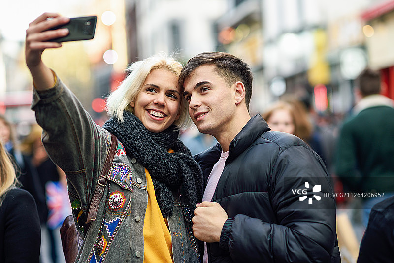 在伦敦拥挤的街道上自拍的快乐游客情侣图片素材