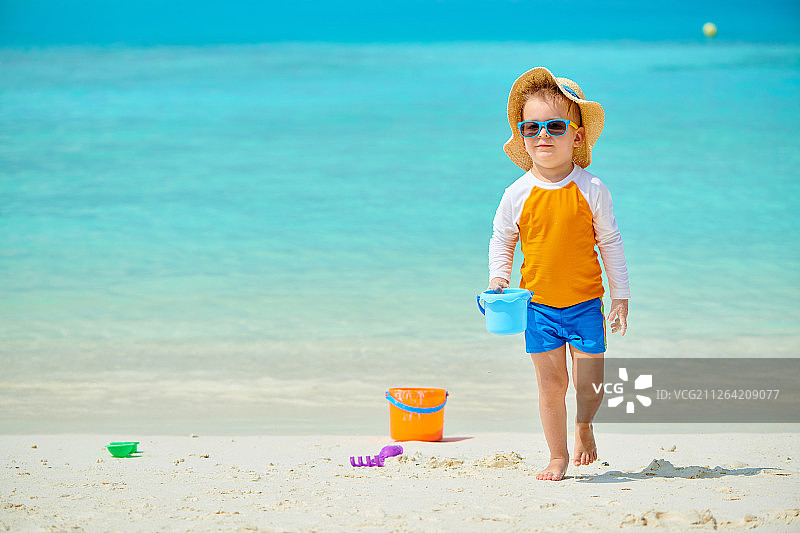 三岁幼儿在海滩上玩沙滩玩具，马尔代夫夏季家庭度假图片素材