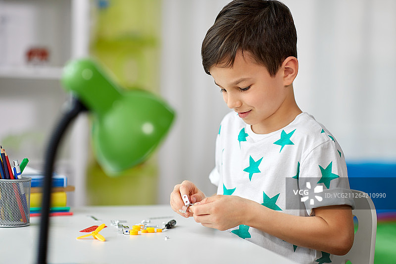 童年爱好休闲概念：小男孩在家玩拼装玩具图片素材