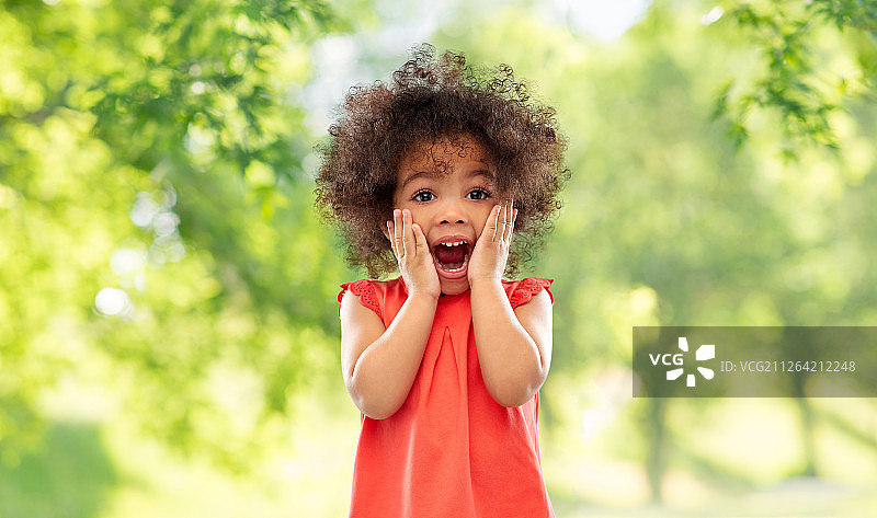童年表情：在绿色夏季背景下，惊讶的非洲裔美国小女孩尖叫图片素材