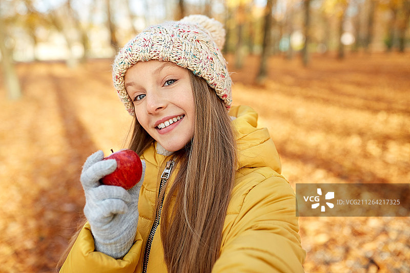 季节与人物概念 - 快乐的女孩在秋季公园用苹果自拍图片素材