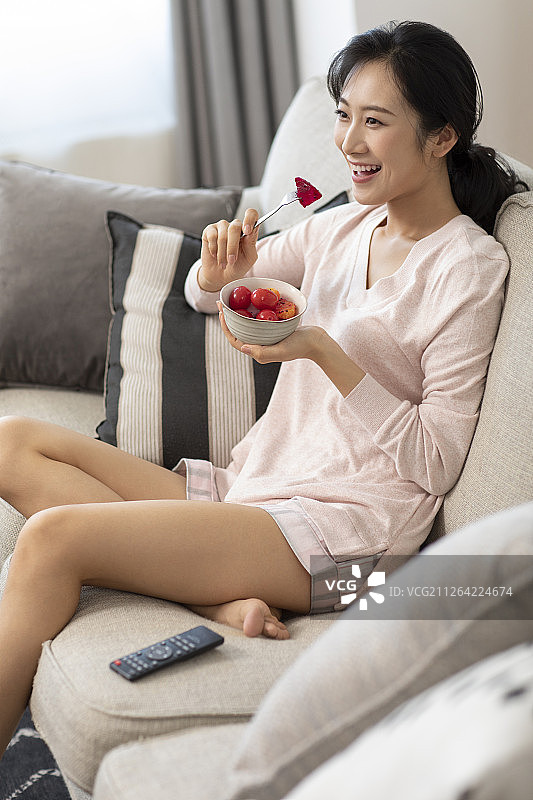 快乐年轻女士在家吃水果沙拉图片素材