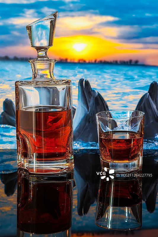 日落时海豚畅游背景上的威士忌酒瓶图片素材