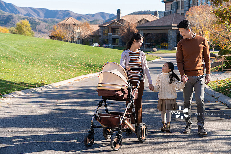 年轻夫妻推着婴儿车散步图片素材