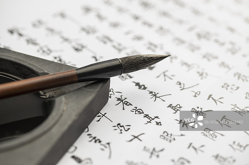毛笔和砚台搁在书写好的字画上面图片素材