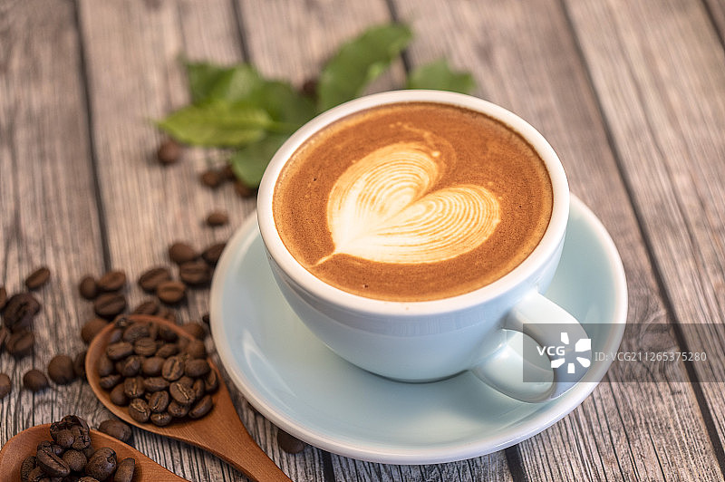 一杯含有爱心图案拉花的拿铁咖啡和咖啡豆图片素材