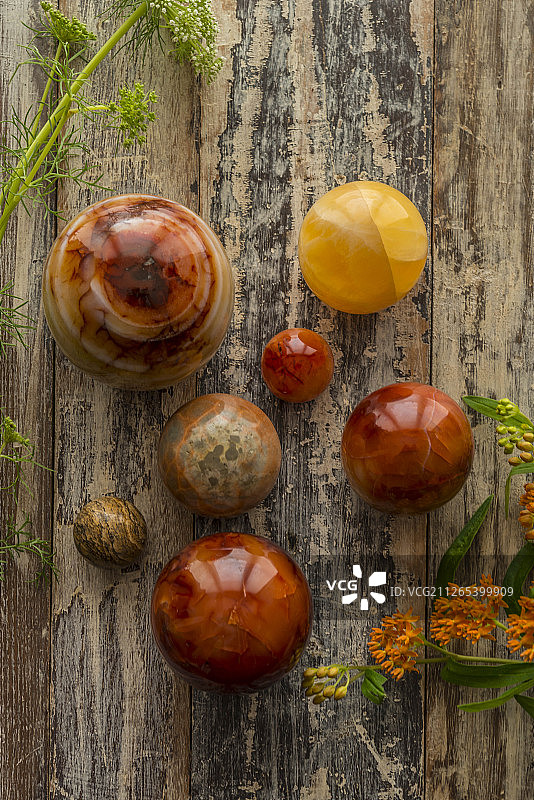 方解石、碧玉、红玉髓和虎眼石抛光球体与秋季花卉图片素材