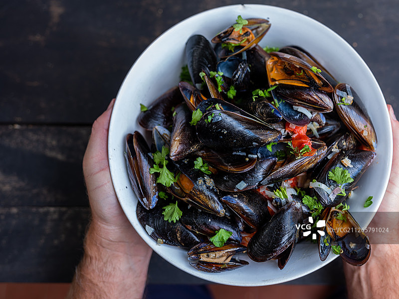 手持白碗里的贻贝图片素材