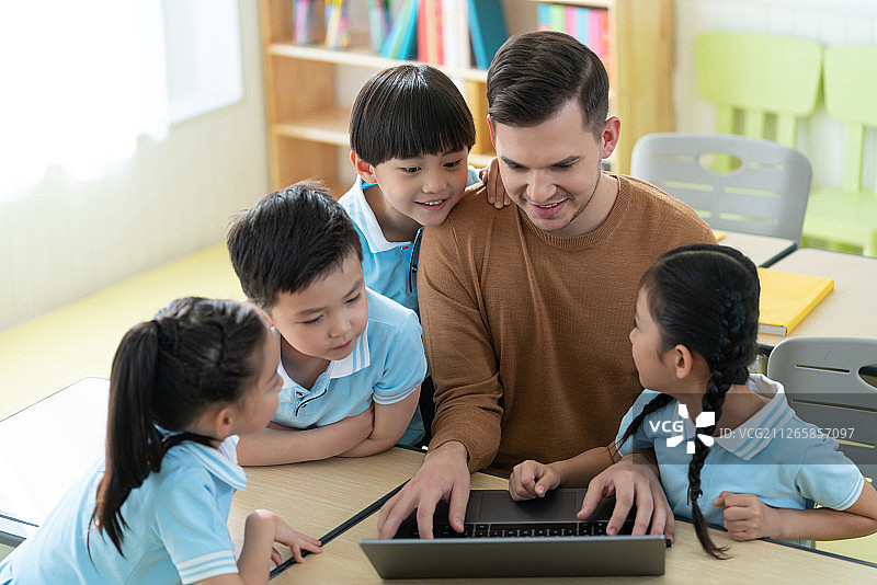 老师在课堂上辅导小学生用电脑图片素材