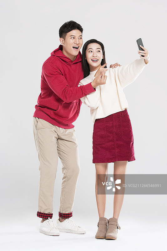 快乐的情侣使用智能手机自拍图片素材