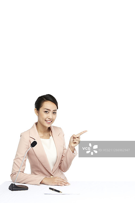 新闻主播坐在新闻台前做手势的摄影图片素材