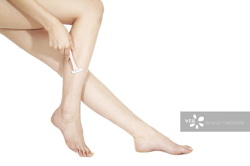 女人用剃刀刮腿毛的摄影照片图片素材