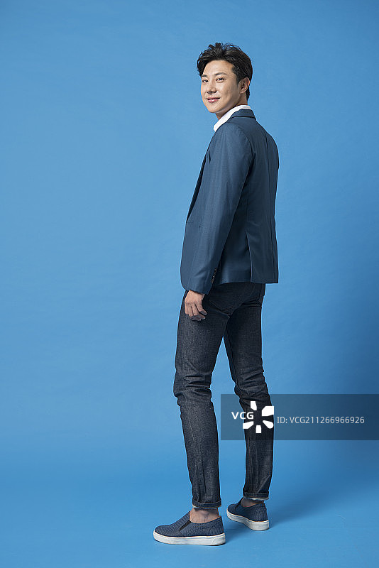 蓝色背景男士回眸站立摄影棚拍摄图片素材