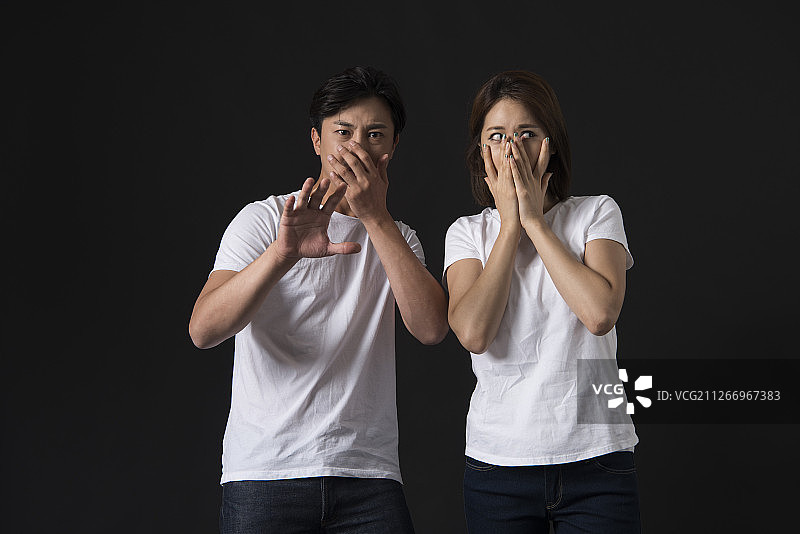 情侣惊恐表情的黑色背景工作室照片图片素材