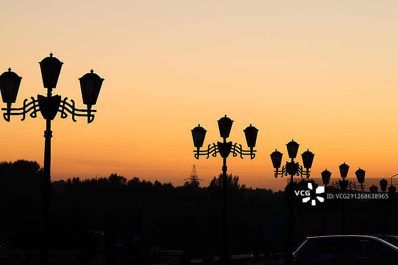 俄罗斯别尔哥罗德的橙色天空下的路灯轮廓图片素材