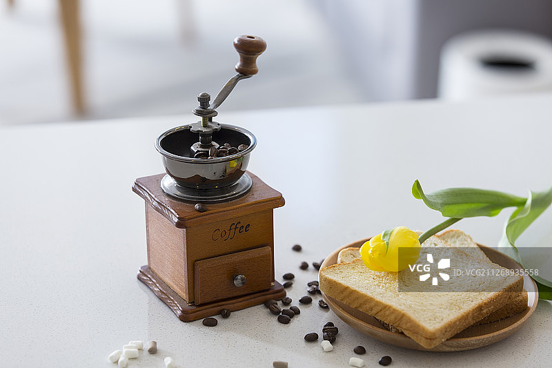 咖啡豆、手磨咖啡机、面包和黄色郁金香图片素材