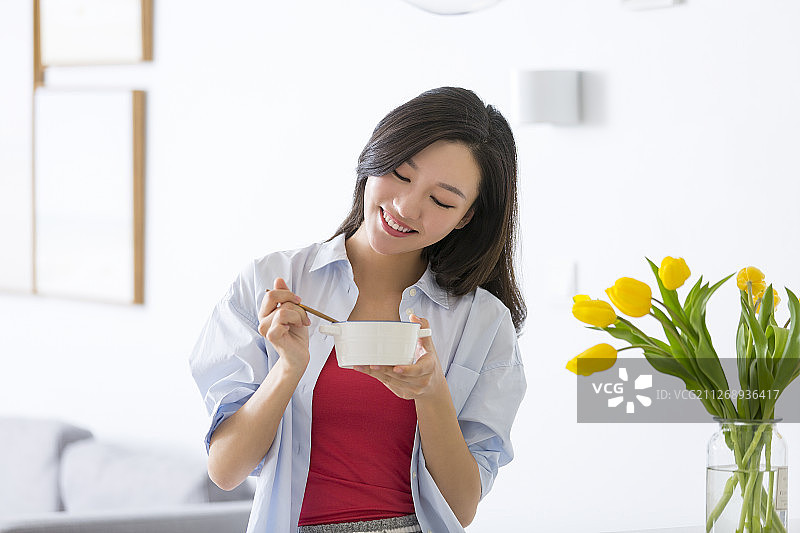 青年女子在客厅吃早餐喝酸奶图片素材