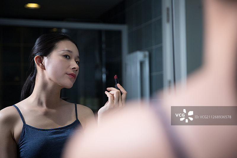 青年女子在卫生间照镜子化妆涂口红图片素材