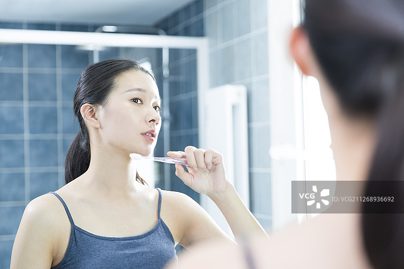 青年女子在卫生间拿着牙刷准备刷牙图片素材