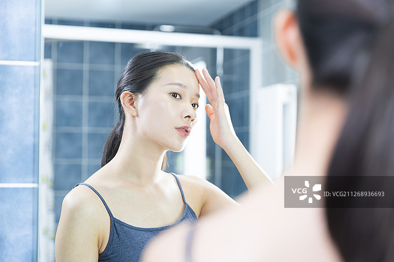 青年女子在卫生间照镜子美容护肤图片素材